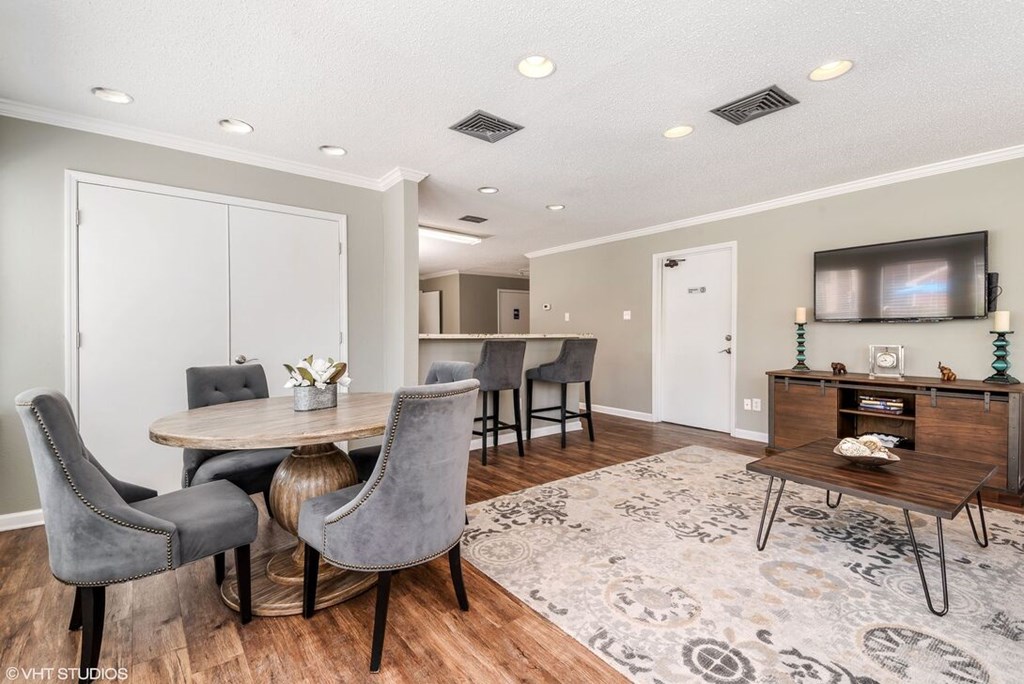 A modern dining room with a round table and grey chairs.
