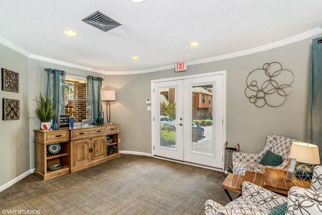 A well-lit room with a wooden cabinet, a chair, and a table with a lamp on it.