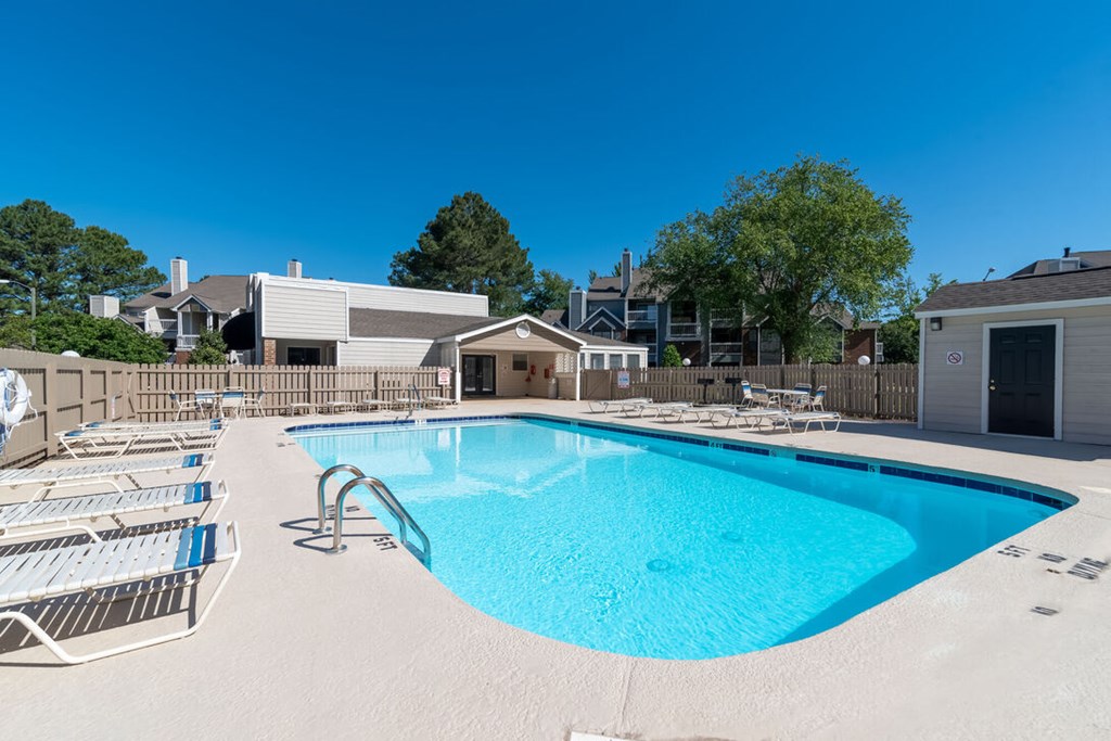 A swimming pool with sun loungers and a building in the background.