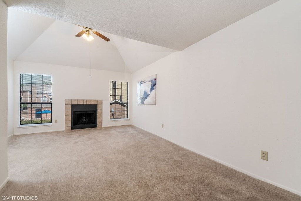 A spacious living room with a fireplace and a painting on the wall.