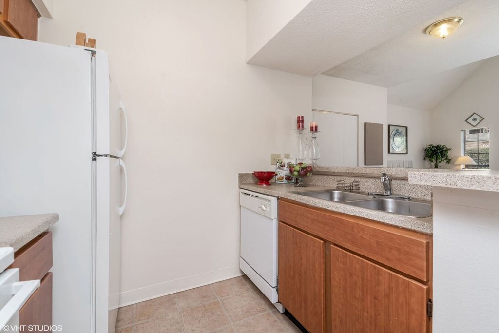 A kitchen with a white refrigerator and wooden cabinets.