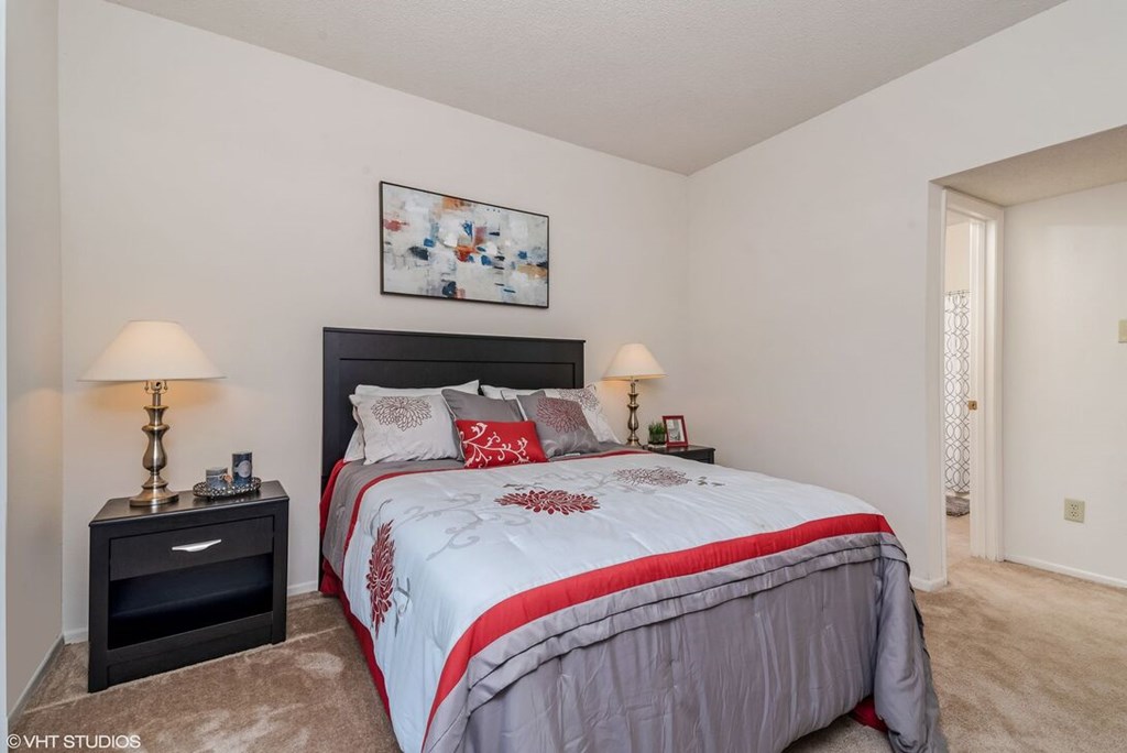 A bedroom with a large bed and a nightstand with a lamp.