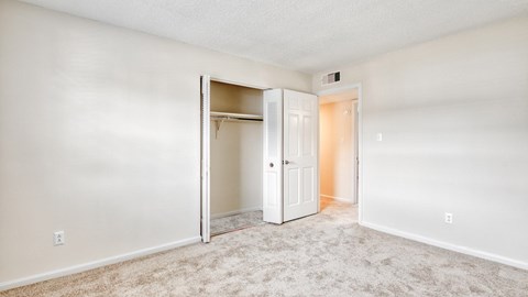 A white bedroom with a closet and carpeted floor.
