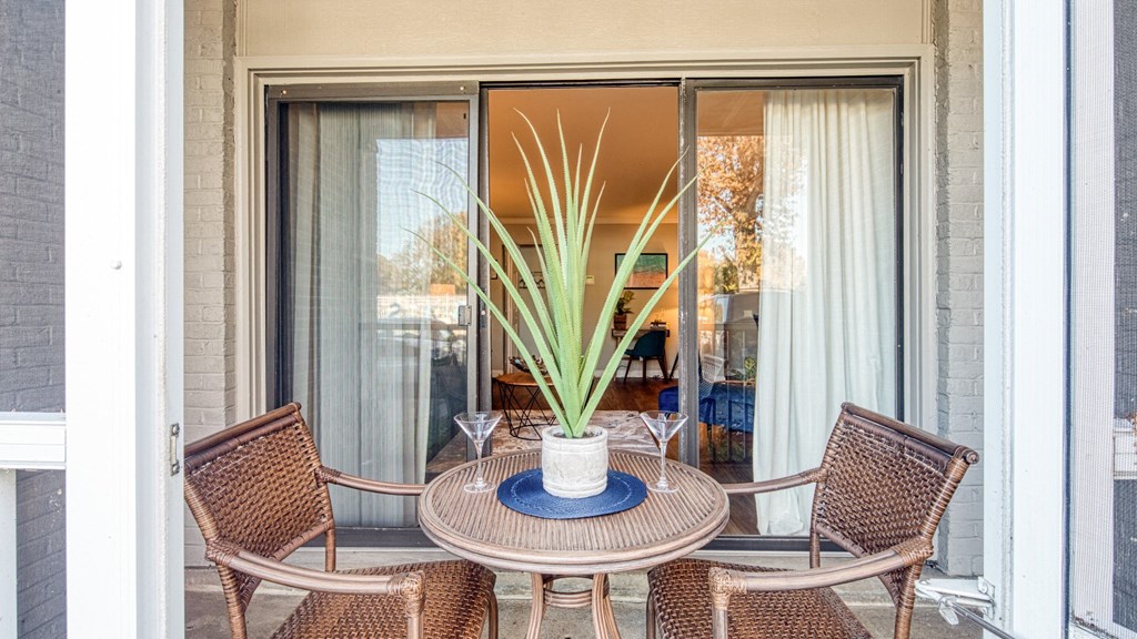 a patio with a table with chairs and a plant on it