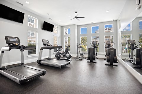 the gym with treadmills and other exercise equipment in a building with windows
