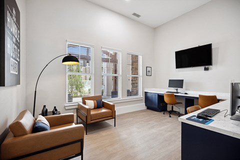 A living room with a brown leather couch, a desk with a computer, and a television mounted on the wall.