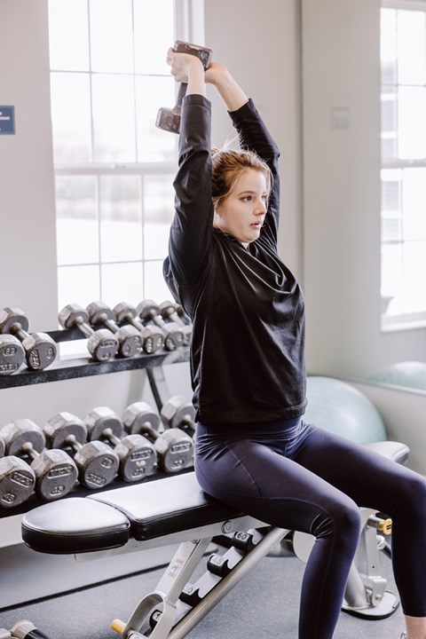 A woman is working out with dumbbells in a gym.