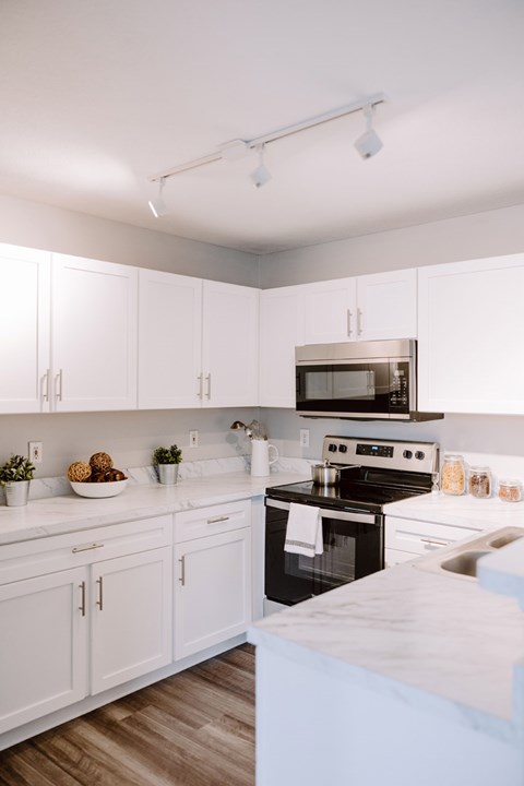 A kitchen with white cabinets and a black stove top oven.