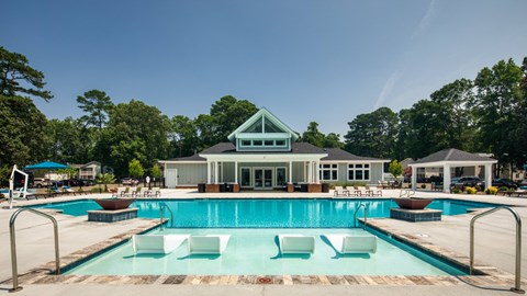 a swimming pool with lounge chairs and a club house in the background