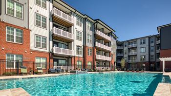 A large swimming pool in front of apartment buildings.