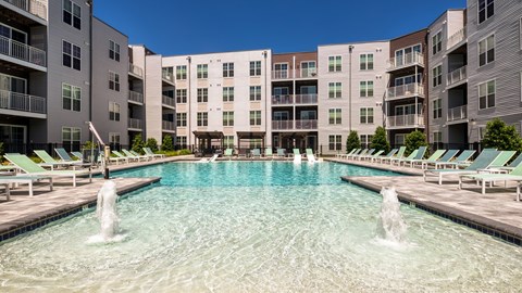 A large pool with fountains in the middle of a residential area.