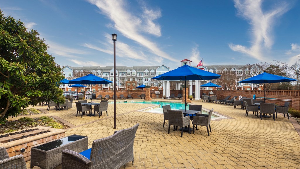 an outdoor patio with tables and umbrellas and a swimming pool