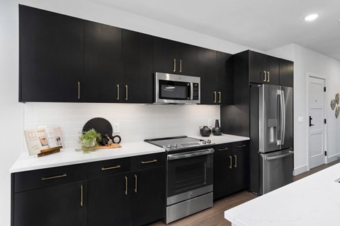 A black and white kitchen with a white counter top.