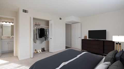 A bedroom with a large bed and a TV on the dresser.