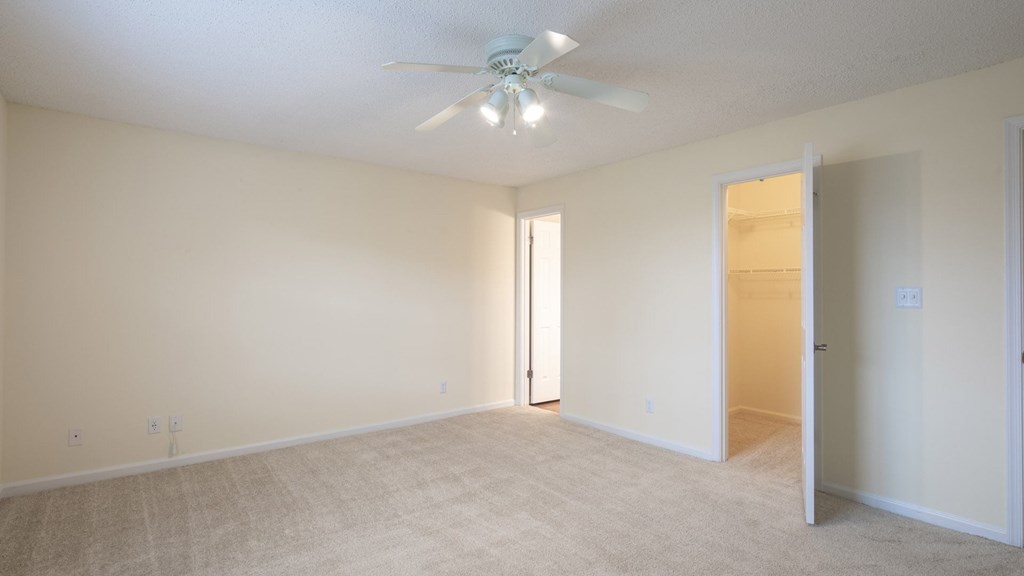 A room with a ceiling fan and carpeted floor.