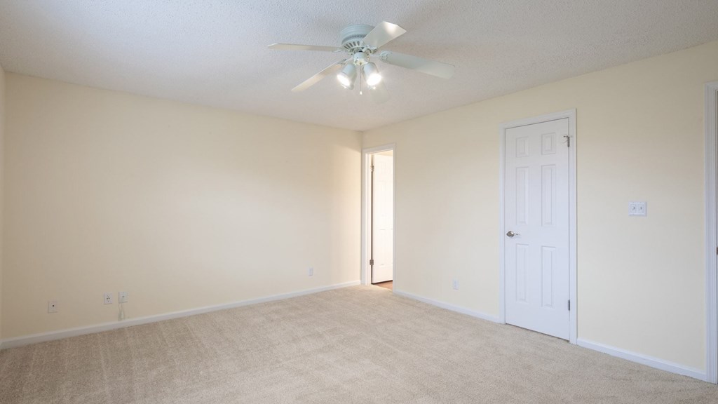 A room with a ceiling fan and carpeted floor.