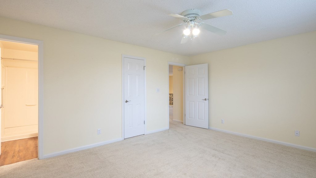 A room with a ceiling fan and two doors.