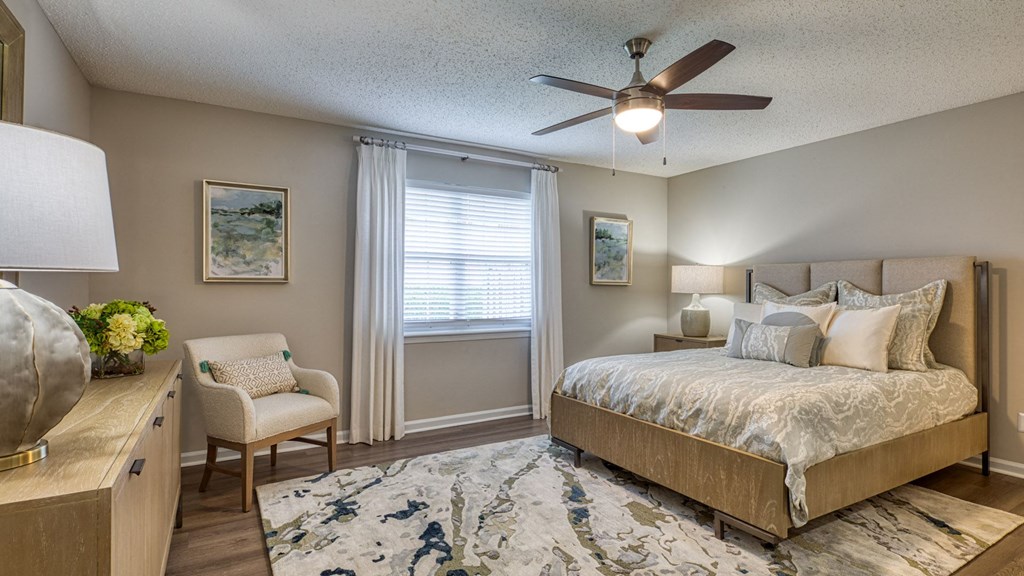 A bedroom with a bed, chair, and a ceiling fan.