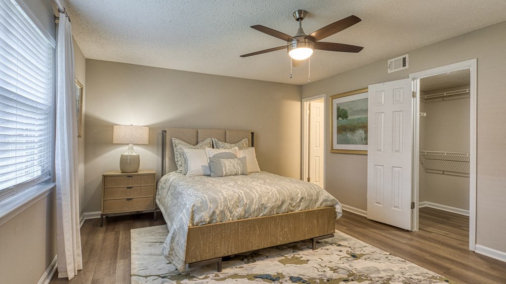 A bedroom with a bed, nightstand, and a ceiling fan.