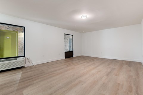 A room with wooden flooring and a white wall with a framed picture hanging on it.