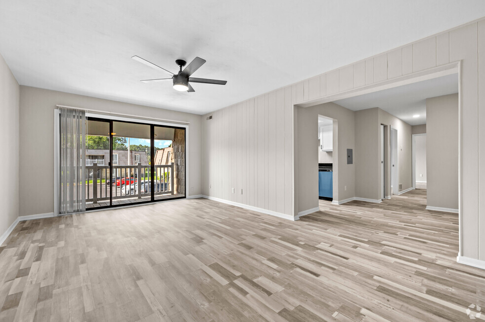 an empty living room with a sliding glass door to a balcony at Bayville Apartments, Virginia Beach
