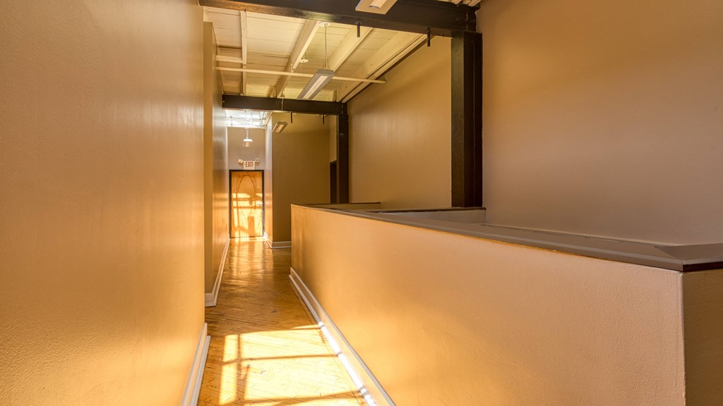 a hallway with a long white wall and a door to a hallway