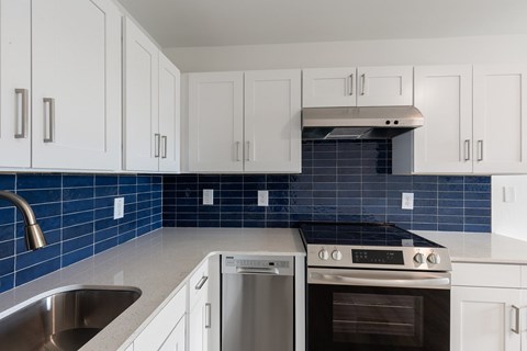 A kitchen with white cabinets and a blue tile backsplash.