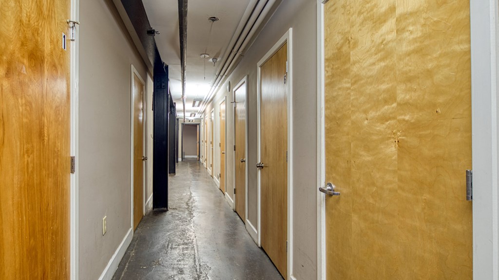 a long hallway with wooden doors and a concrete floor