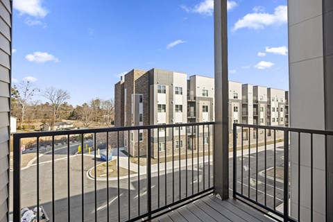 A view from a balcony overlooking a parking lot and apartment buildings.