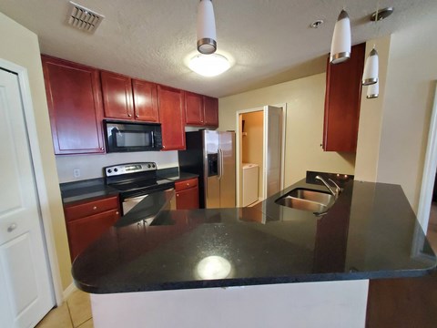 A kitchen with a black counter top and wooden cabinets.