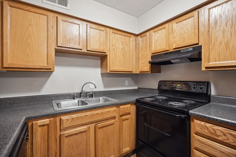 A kitchen with wooden cabinets and a black stove top oven.