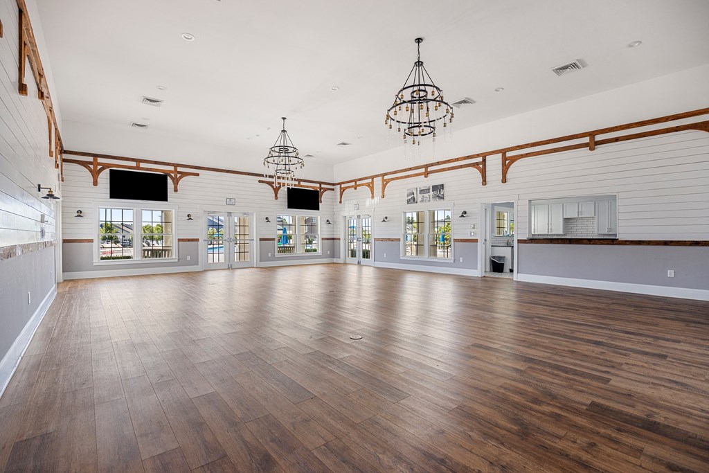 the spacious dance room with wood floors and chandeliers