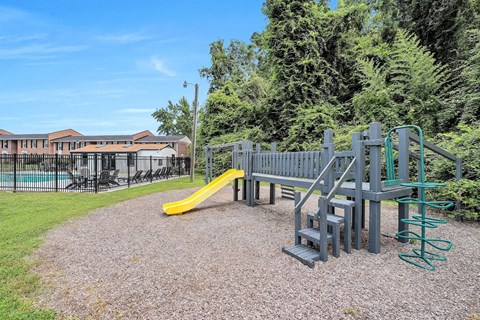 A playground with a yellow slide and a green spring rider.