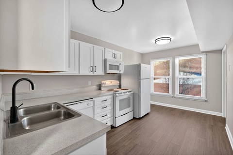 A kitchen with white cabinets and a grey countertop.