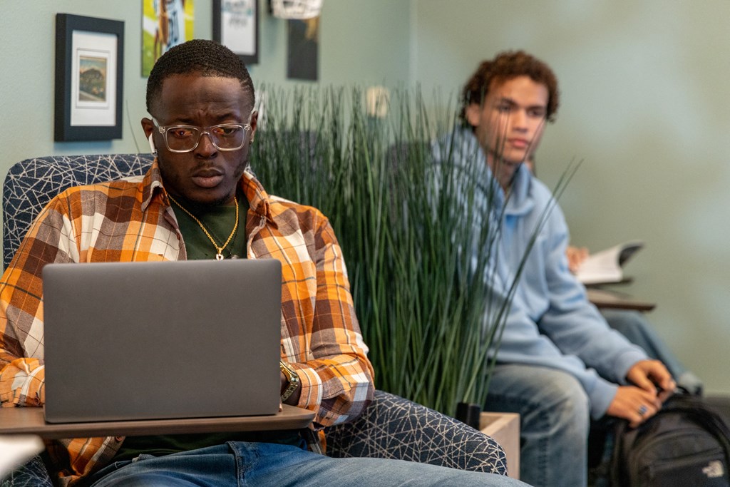 two men sitting at a table with a laptop computer