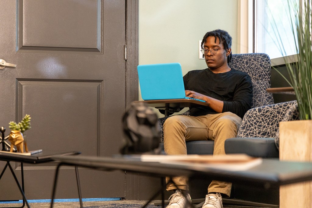 a man sitting in a chair with a laptop on his lap