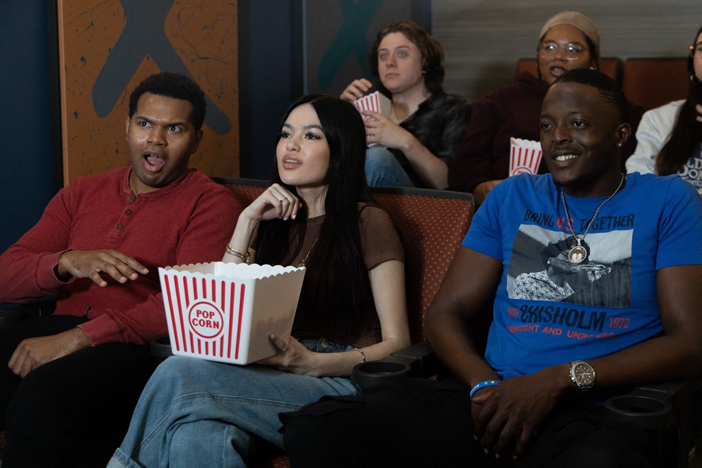 a group of people sitting in a movie theater eating popcorn