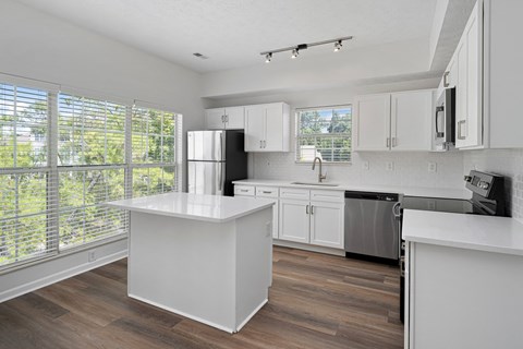 A kitchen with white cabinets and a large island.