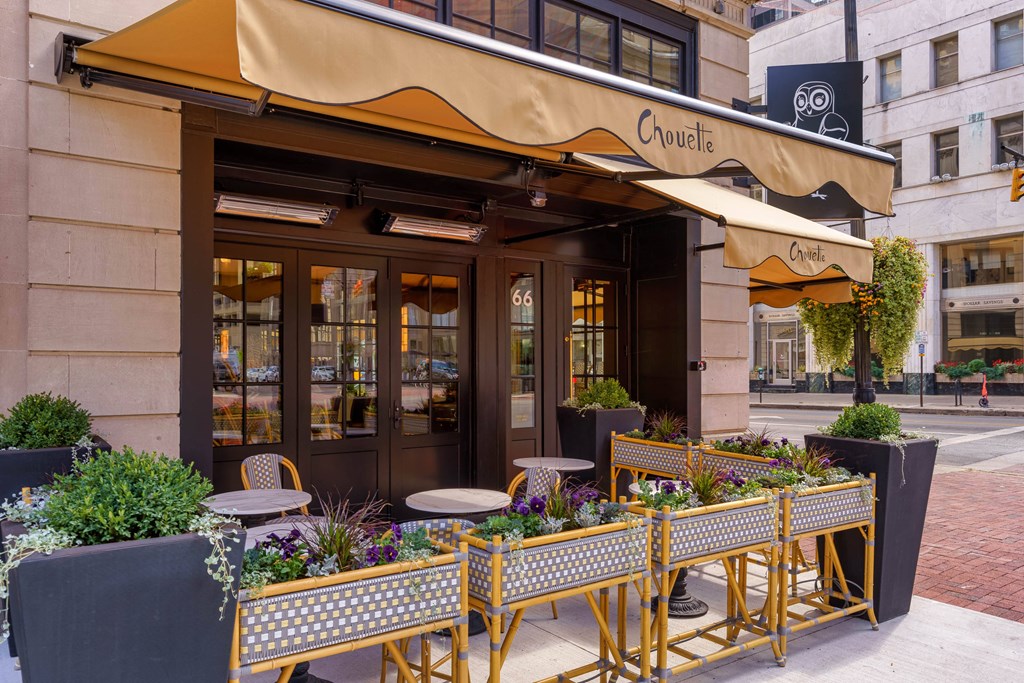 A restaurant named Chouette has a yellow awning and a table set up outside at The Madison in Columbus, OH 43215