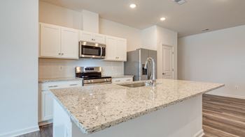 a kitchen with a granite counter top and a sink at The Mark Townhomes Apartments, Harrisonburg, VA