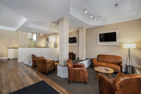 A living room with brown leather chairs and a white reception desk.