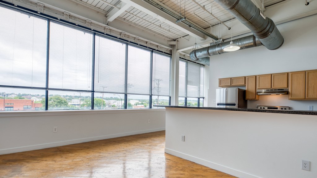 an empty room with a large window and a kitchen at The Hudson, Richmond, 23224