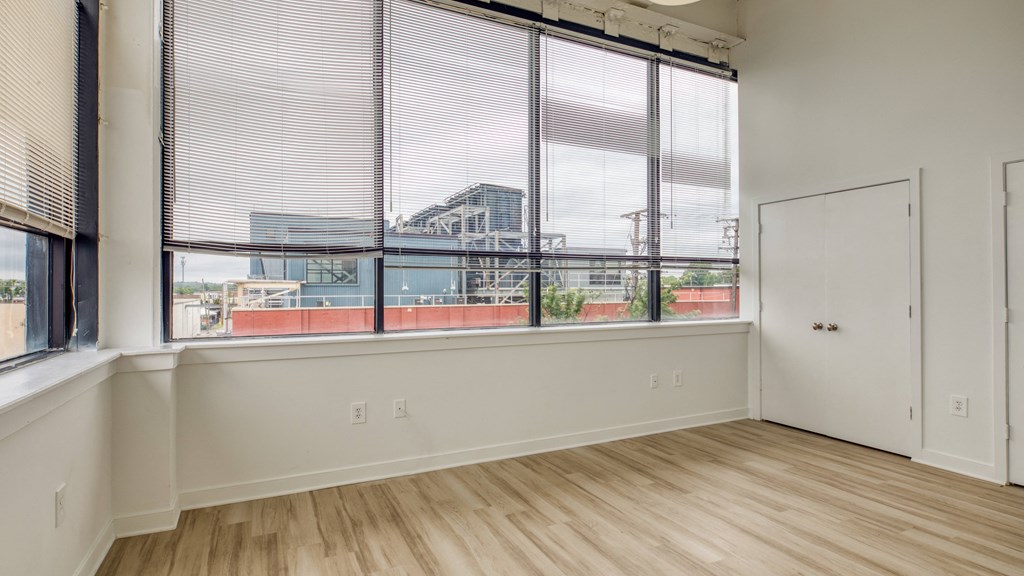 an empty room with a large window with blinds and a white door  at The Hudson, Richmond