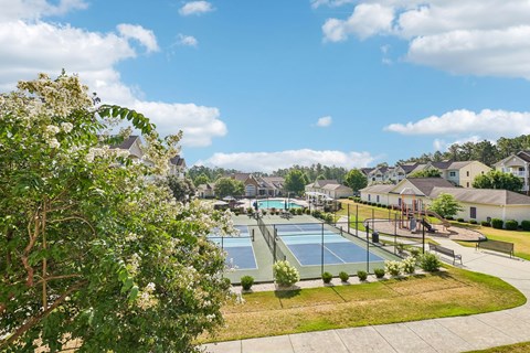 A tennis court is surrounded by houses and trees.