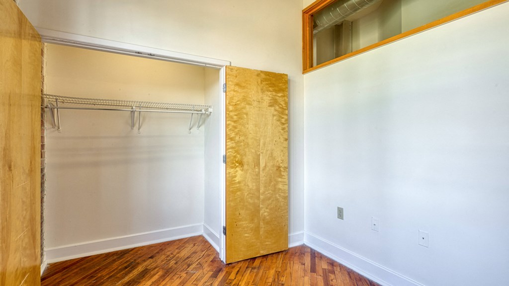an empty room with a wooden floor and a closet with a mirrored door