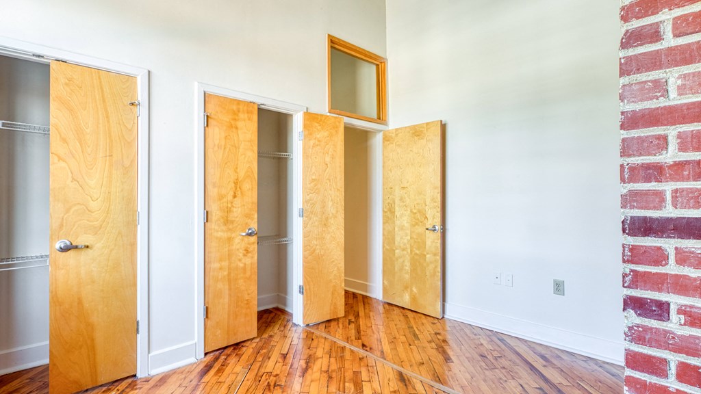 a row of doors in a room with wood floors and a brick wall