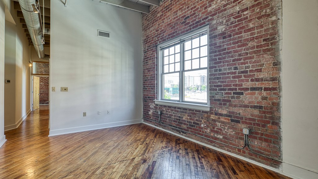 an empty room with a brick wall and a window