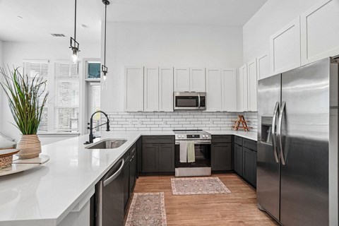 A modern kitchen with a stainless steel refrigerator and black cabinets.