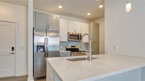 a kitchen with a sink and a stainless steel refrigerator