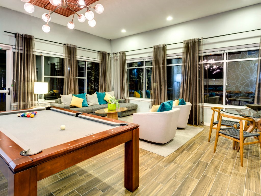 A pool table is in the middle of a living room with a couch and a chair.